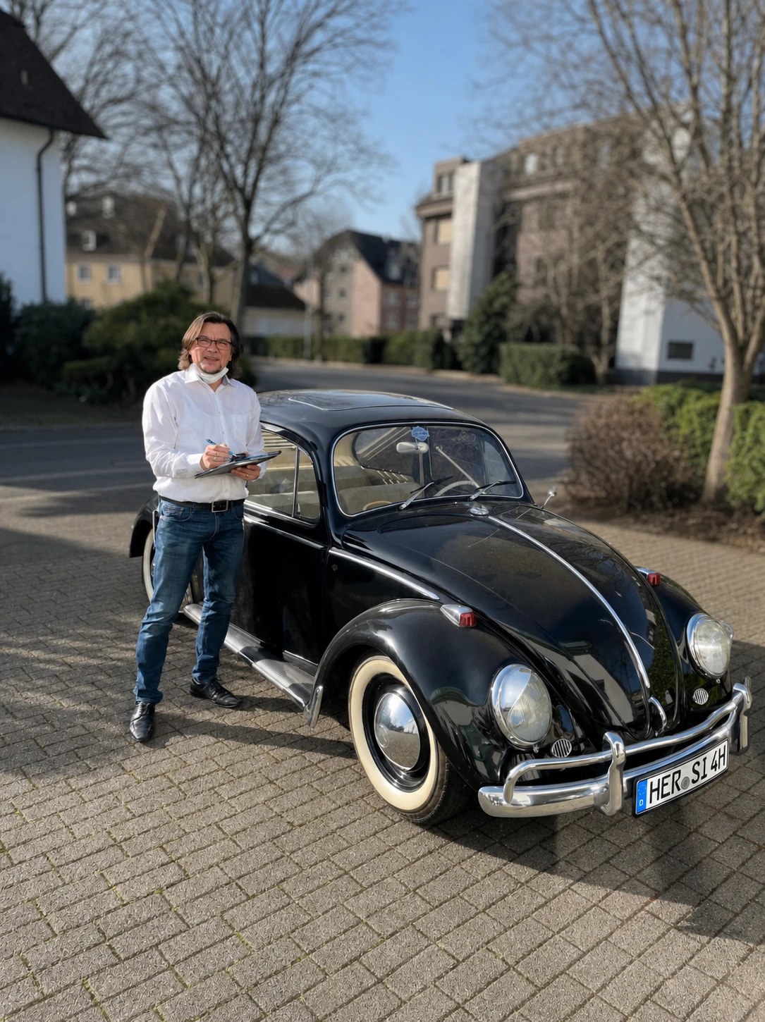 Christian Mastria notiert am Klemmbrett neben einem schwarzen VW Käfer
