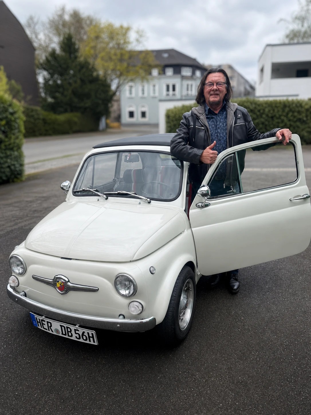 Christian Mastria an einem cremefarbenen Fiat 500 mit geöffneter Tür