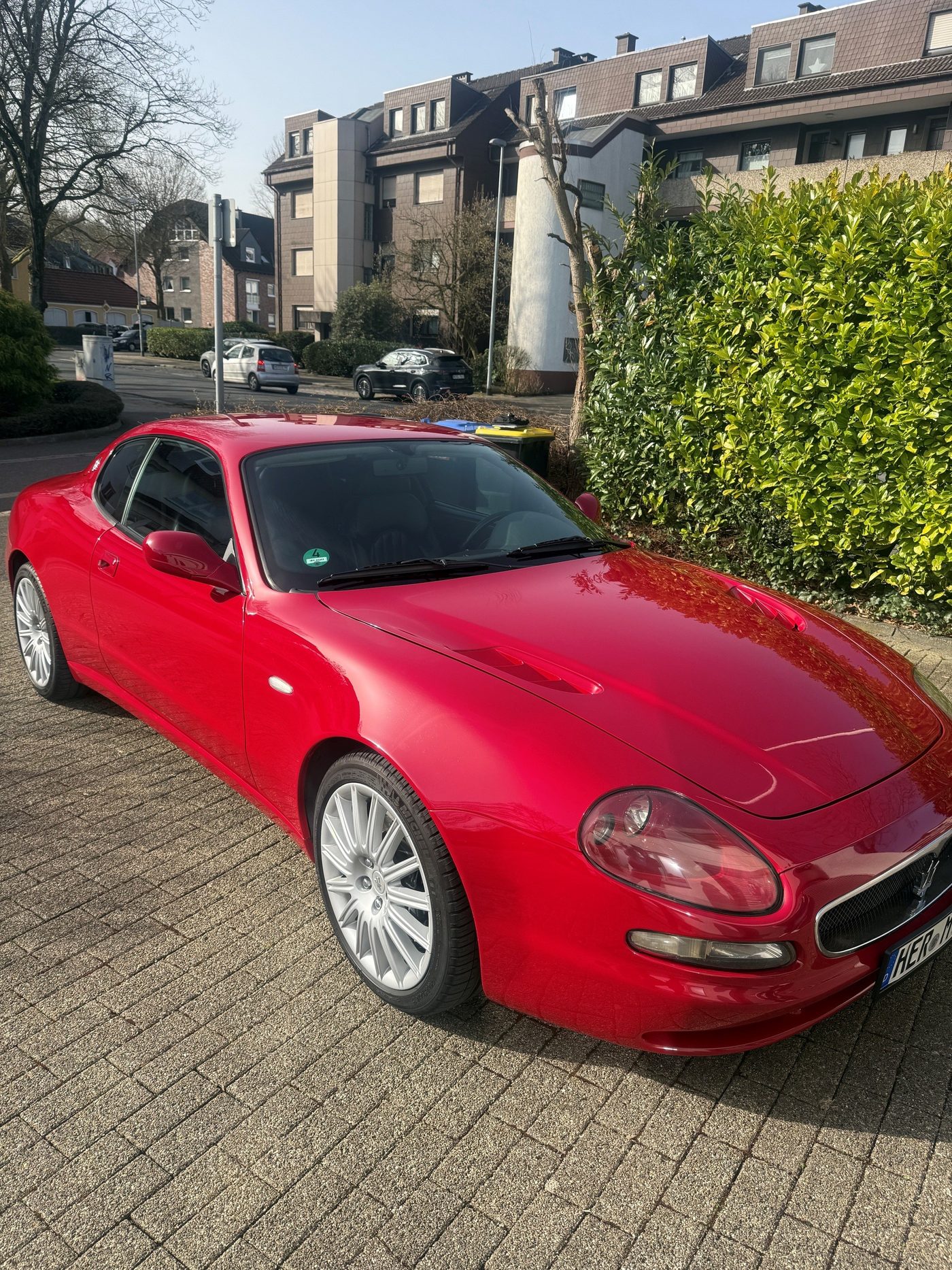 Roter Maserati Coupé auf gepflastertem Hof
